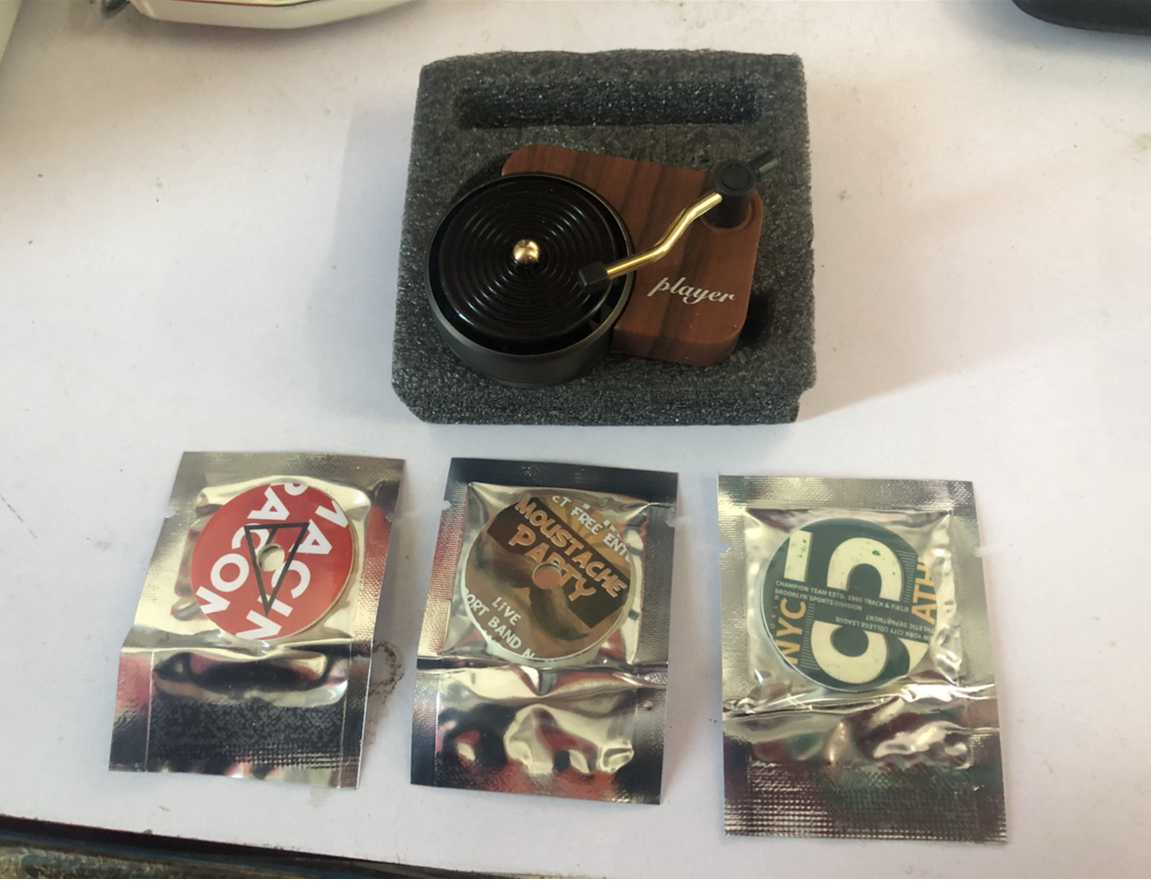 Miniature wooden turntable with player label and three different vinyl record stickers.